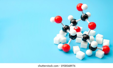 Azúcares simples, conciencia de la diabetes y estructura química del concepto de hidratos de carbono con modelo plástico de molécula de glucosa y cubos de azúcar aislados en fondo azul con espacio de copia