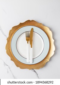 Simple table set with golden and white tableware on white marble. Gold fork and knife at white blue plate with gold dish - Shutterstock ID 1894368292