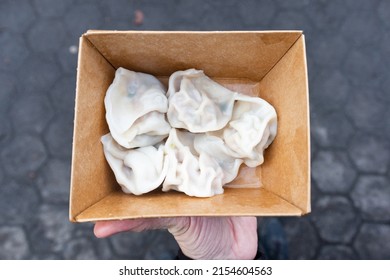 Simple Takeout Box Of Boiled Chinese Pork Dumplings Held By A Hand