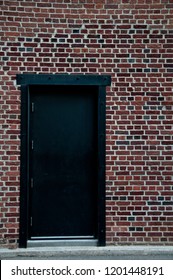 Simple vertical image of a brick wall with black door