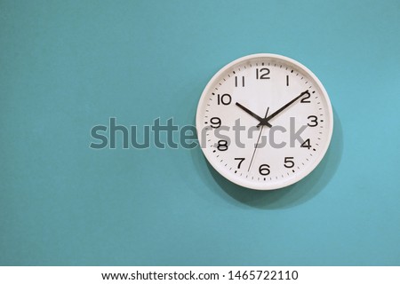 Simple wall clock hanging on a blue wall