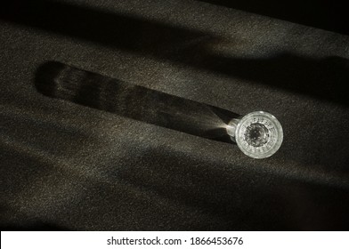 A Simple Water Glass With Sparkling Water Casts A Long Diagonal Shadow On A Black Granite Slab From Top View