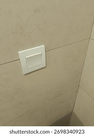 A simple white light switch mounted on a textured wall in a home