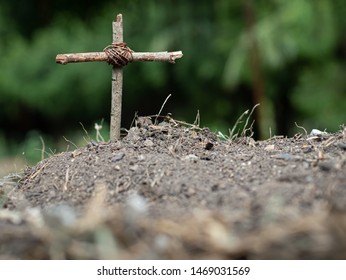 Simple Wooden Christian Cross On A Simple Grave Of Mounds.