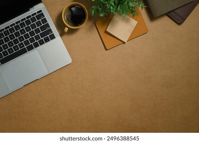 Simple workspace with cup of coffee, book and potted plant on brown background. Top view, flat lay.