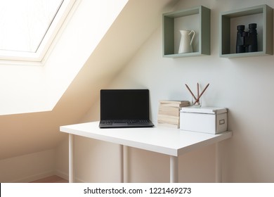 Simple workspace interior under skylight window in attic / loft. Laptop computer and a pile of books on a white modern office desk. - Powered by Shutterstock