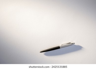 Simple yet elegant classic ballpoint pen resting on a pure white paper, symbolizing potential creativity or work.