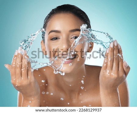 Simplicity is the beauty of life. Shot of a young female washing her face against a blue background.