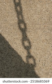 A simplified shadow of a typical chain falling on the concrete ground.