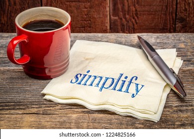 simplify advice -  handwriting on a napkin wioth a cup of coffee against rustic wood