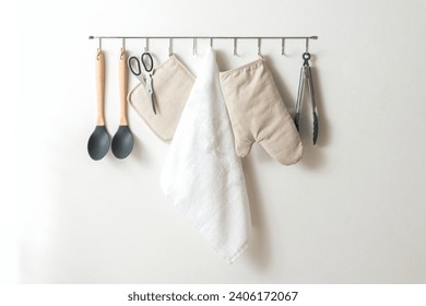 Simplistic Kitchen Wall Organization with Modern Utensils: Silicone-Tipped Wooden Spoons, Stainless Steel Scissors, Natural Fabric Potholder, White Terry Towel, and Tongs, all under Soft Lighting.