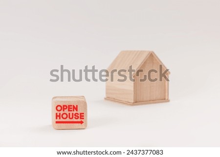 Simplistic wooden house model isolated on pale green background, with text Open House on signboard.