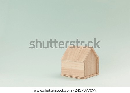 Simplistic wooden house model isolated on pale green background