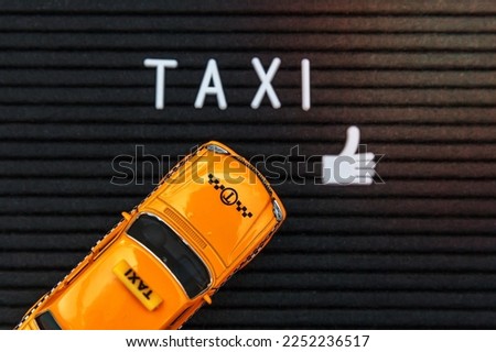 Simply design yellow toy car Taxi Cab model with inscription TAXI letters word on black background. Automobile and transportation symbol. City traffic delivery urban service idea concept. Copy space