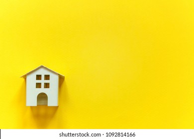 Simply flat lay design with miniature white toy house on yellow colorful paper trendy background. Mortgage property insurance dream home concept