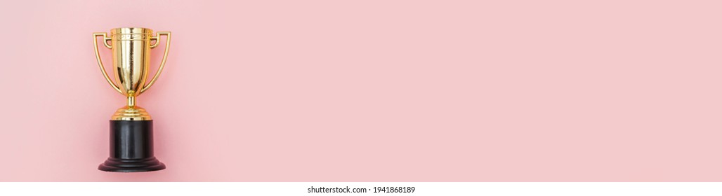 Simply Flat Lay Design Winner Or Champion Gold Trophy Cup Isolated On Pink Pastel Colorful Background. Victory First Place Of Competition. Winning Or Success Concept. Top View Copy Space Banner