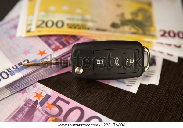 Simulation loan foCar key and Euro banknotes on\
brown background with shallow depth of fieldr car purchase. Five\
hundred Euro banknotes and car\
keys.