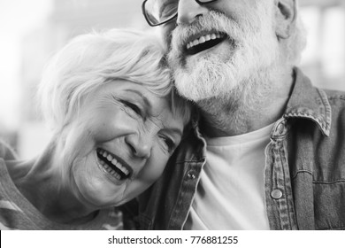 Sincere emotions. Close up black-and-white portrait of mature married man and woman bonding to each other while laughing. Happy retirement concept
