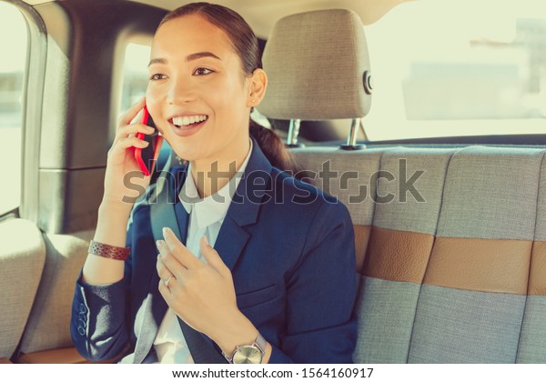 Sincere emotions. Delighted\
businesswoman keeping smile on her face while talking per\
telephone