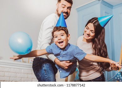 Sincere emotions. Energetic happy family laughing while parents lifting boy