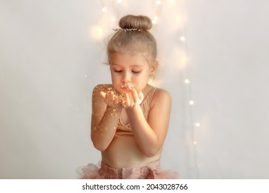 Sincere happiness. Happy joyful girl holding her hands and blowing gold glitter. 