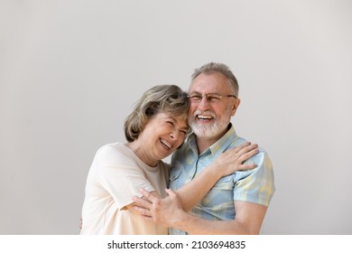 Sincere laughing bonding happy middle aged senior married couple cuddling, having fun enjoying communicating, isolated on white wall, showing candid loving feelings, good family relations concept. - Shutterstock ID 2103694835