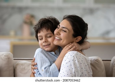 Sincere loving young Indian woman cuddling cute little kid son, showing tender feelings. Happy two generations family enjoying sweet weekend moment together, relaxing at home.