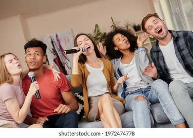 Sing As You Can. Enthusiastic Group Of Friends Singing With Microphone While Playing Karaoke At Home, Sitting On The Couch At Home