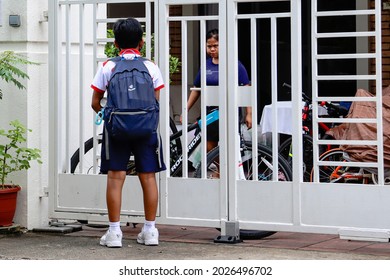 SINGAPORE - 1 AUG 2021: The Filipino Foreign Domestic Worker Frowns At The Boy Who Has Pressed The Gate Bell Too Many Times To Get Her To Unlock The Gate To Go Home. She Tells Him To Be Patient.