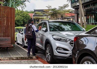 SINGAPORE - 1 JUL 2021: An auxiliary police parking warden uses the Electronic Handheld Terminal Scanner to issue a summons to the driver for failure to use his CAR PARKING APP to pay his parking.   - Shutterstock ID 2012000216