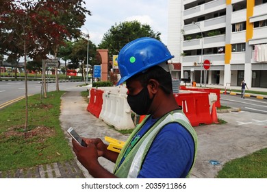 SINGAPORE -1 SEP 2021: A Masked Bangladeshi Migrant Construction Worker Is The Safety Supervisor In Bishan. He Texts Messages Or Add Post To His Facebook. He Lives In A Dormitory Sharing 12 To A Room.