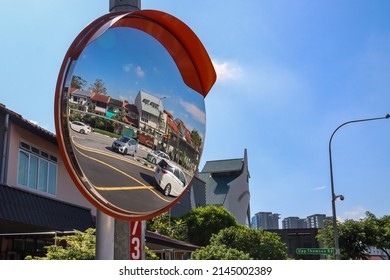 SINGAPORE - 10 APR 2022: A convex mirror at Upper Thomson Rd shows a wider view of cars making U-turn at the box junction (R) to warn approaching drivers to drive with care.