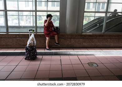 Singapore - 11th November 2021: An Elderly Lady Is Talking On The Phone At A Train Station.