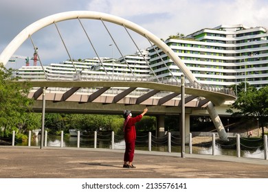SINGAPORE - 14 MAR 2022: 9 AM. An elderly resident take photos of the clear riverfront scenery of Watertown, Punggol. Early morning walks and sunshine promote physical and mental health of seniors.   