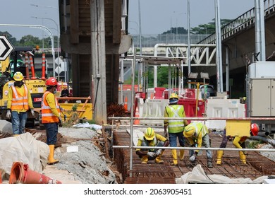 SINGAPORE - 15 OCT 2021: Migrant construction workers pour cement to build a new pavement in the Lentor Ave site of the North-South Corridor project. 