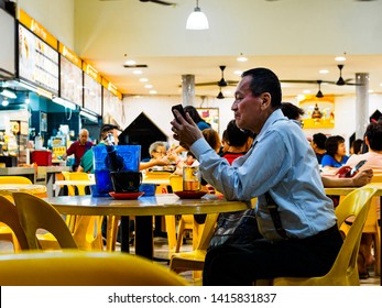 SINGAPORE - 17 MAR 2019 - A Middle Aged Asian Chinese Singaporean Man In Office Attire Enjoys A Late Night Beer At An Eatery / Coffeeshop / Kopitiam, / Hawker Centre In Singapore