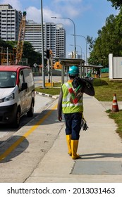 SINGAPORE - 2 JUL 2021: A North-South Corridor Construction Migrant Worker At Ang Mo Kio Waits To Cross The Road.  The Construction Industry Is Highly Dependent On Foreign Workforces From South Asia. 