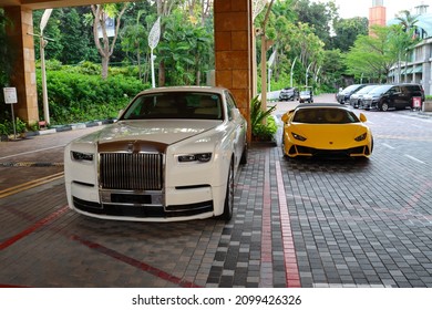 SINGAPORE - 21 DEC 2021: A white Rolls-Royce car (L) parked outside Hotel Michael in Sentosa. Around 400 Rolls-Royce cars are present in Singapore. Each new luxury car costs over S$1.0 million. 