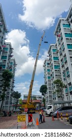 Singapore, 21 July 2022. Lorry Crane Lifting Pipes Between Public Housing In Singapore.