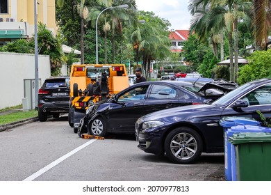 SINGAPORE - 31 OCT 2021: A Yellow Tow Truck Hooks Up The Stolen Accident Car To Tow It Back To The Workshop. A Young Man Had Smashed Its Front And Back Into 3 Cars When Pursued By An Unmarked Car.