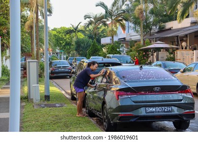 SINGAPORE - 4 JUN 2021: A Foreign Domestic Worker (FDW) Washes Her Employer's Car. FDWs Do General Housework, Cook, Care For The Family Members With Disabilities, The Elderly And The  Younger. 