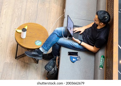SINGAPORE - 7 JUL 2021: A man has breakfast and works from a coffee cafe at Jewel Changi Airport instead of the office, to avoid the Delta variant Covid-19 viral transmission. He can work from home.