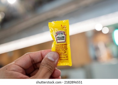 SINGAPORE - APR 20, 2022:Hand Holding A Sachet Of Heinz Yellow Mustard With Blur Background