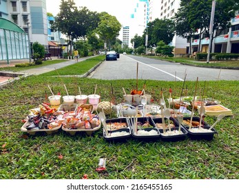 Singapore Aug2021 Lavish spread of food and drinks with joss paper, incense placed on grass in neighbourhood heartland as offerings during the 7th month Hungry Ghost Festival (texture in road, grass)