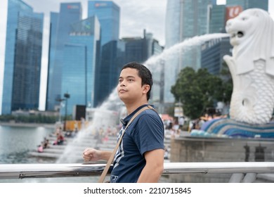 SINGAPORE - August 20, 2022 : Merlion Statue Fountain With Asian Tourist Man In Merlion Park.