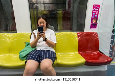 SINGAPORE - CIRCA OCTOBER, 2018:   A Lady Playing Smart Phone While Inside The Train In Singapore. MRT Is A Major Component Of The Railway System In Singapore.