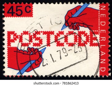 SINGAPORE - DECEMBER 27, 2017: A Stamp Printed In The Netherlands, Dedicated To The Introduction Of New Postal Code, Shows The Hand Of A Writing Text, Circa 1979