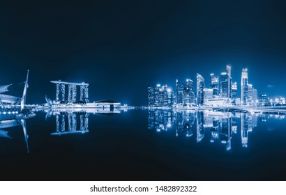 Singapore Downtown Skyline At Night With Reflection. Financial District And Business Centers In Technology Smart Urban City In Asia. Skyscraper And High-rise Buildings.