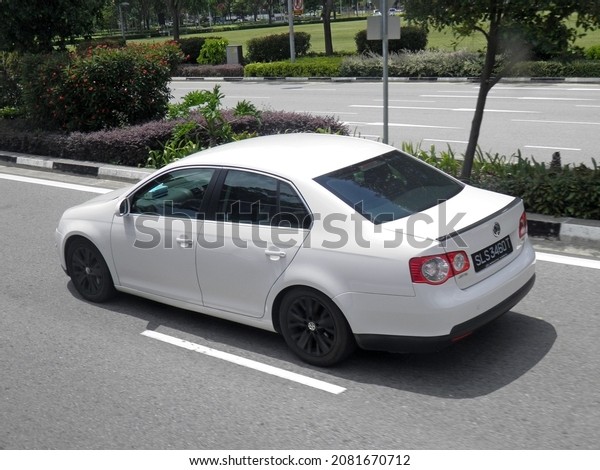 Singapore, february 17 2020: private front-wheel fwd\
drive white metallic color european midsize old compact sedan\
Volkswagen Jetta 1K2 popular small car made in Germany drive on\
sunny highway street\
