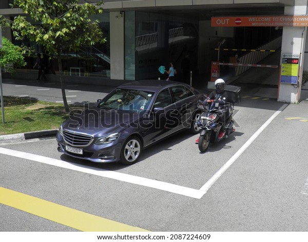 Singapore, february 17 2020: private purple\
metallic color germany sedan Mercedes-Benz E-klasse W212 facelift\
and japanese Yamaha motorcycle, luxury car made in Germany drive on\
city urban street